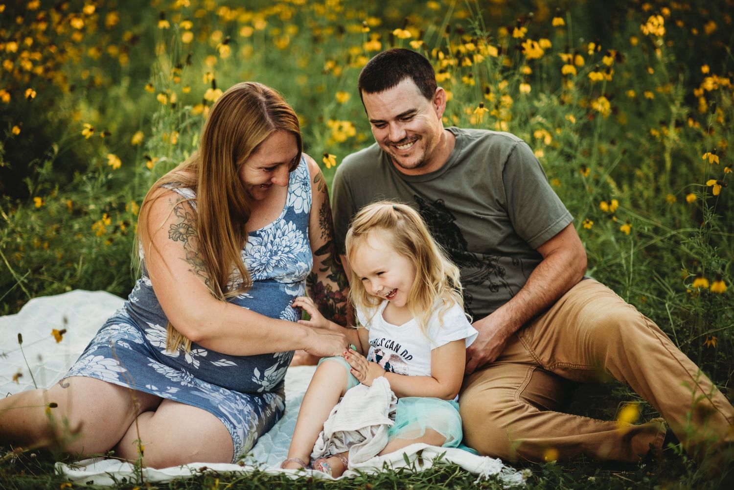 Family enjoying picnic together among yellow wildflowers at sunset.