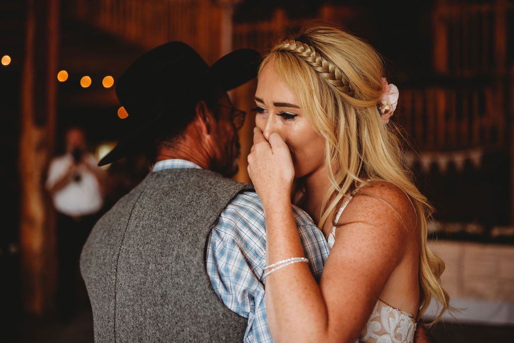 Emotional wedding moment captured during a first dance in a rustic venue with warm lighting.