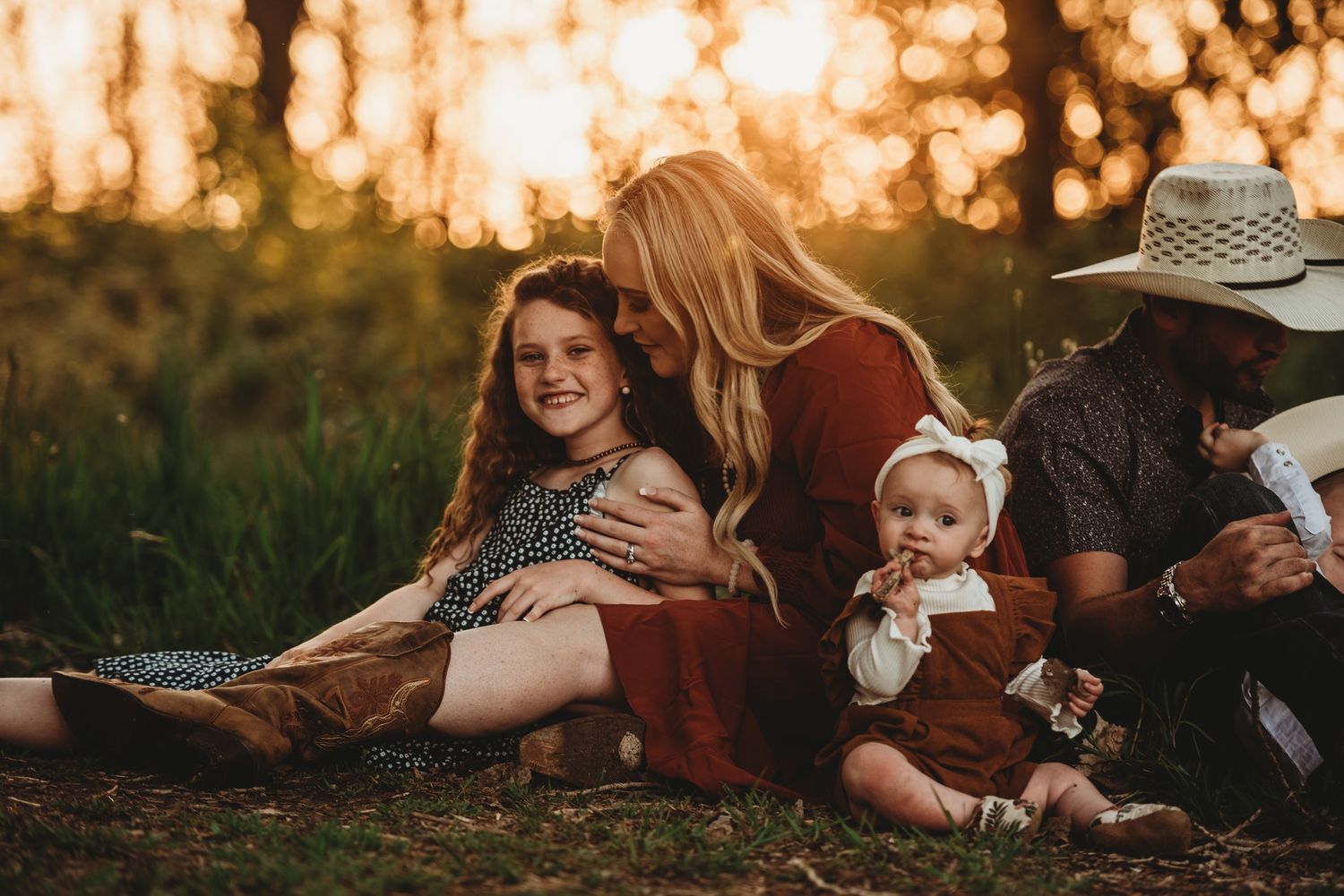 Candid family moment at golden hour in field with children.