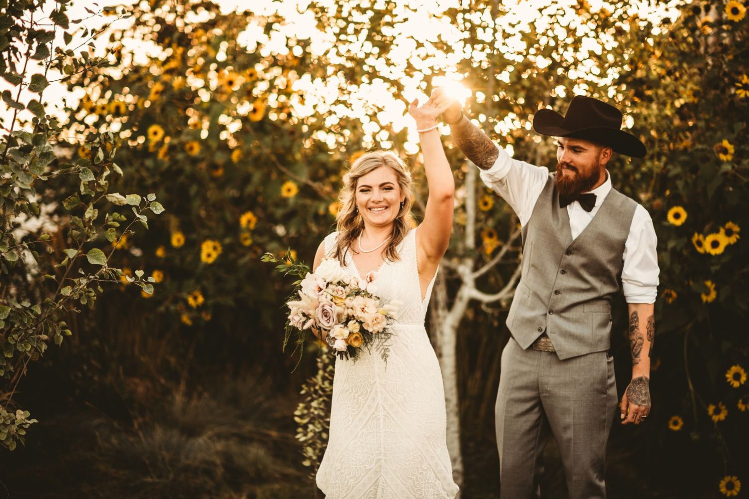 A couple celebrates during their sunset wedding ceremony in a field of sunflowers, bride in white dress with bouquet.