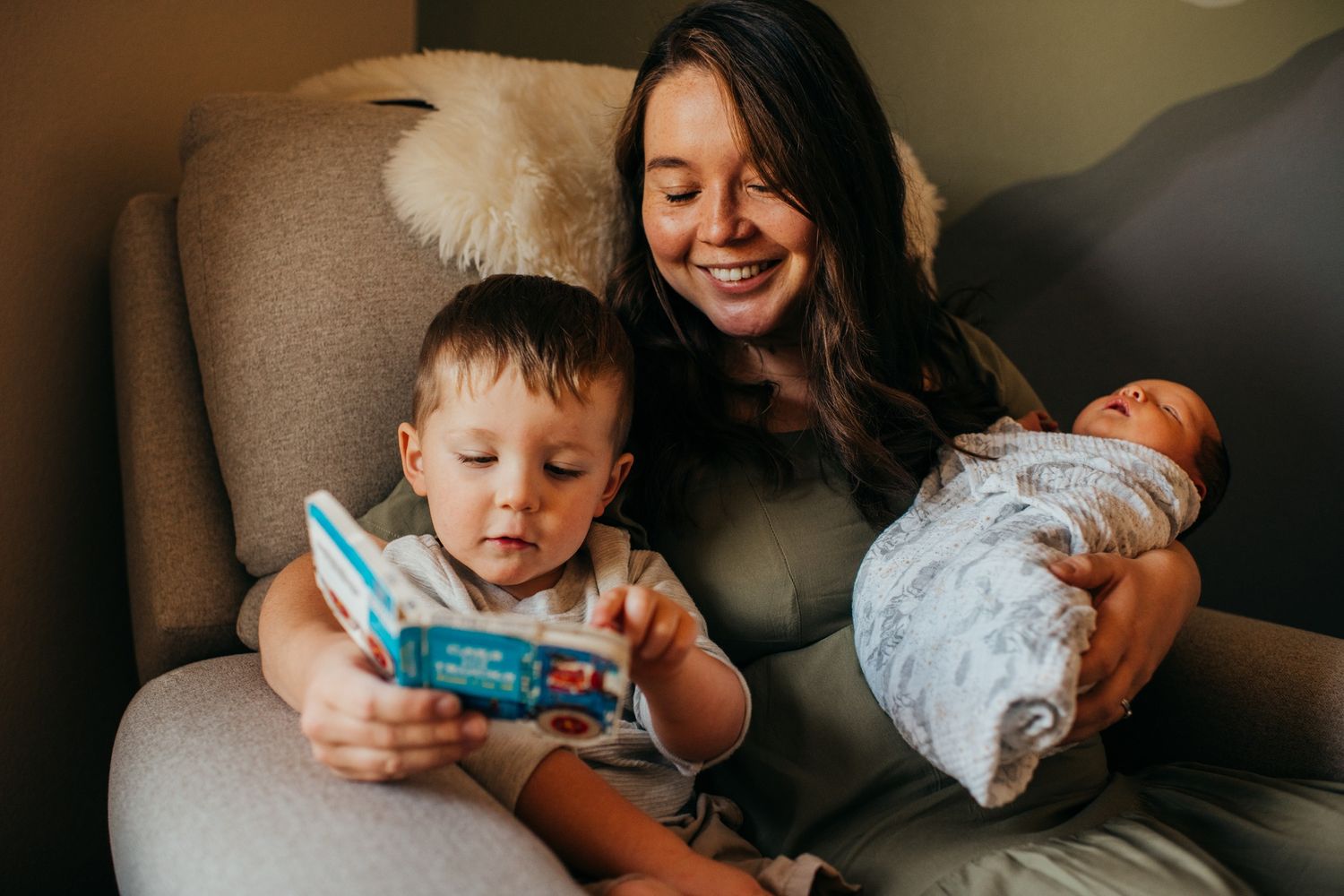 A relaxed family moment on a grey armchair with handheld electronics.