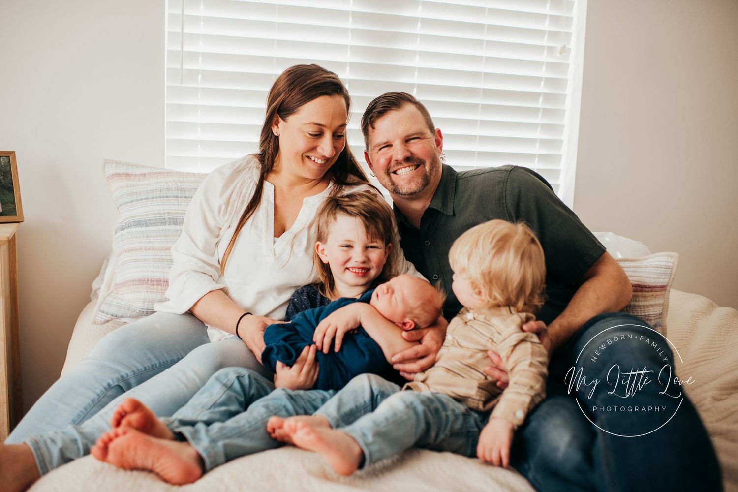 A cozy family moment captured on a bed with joyful expressions and casual attire.