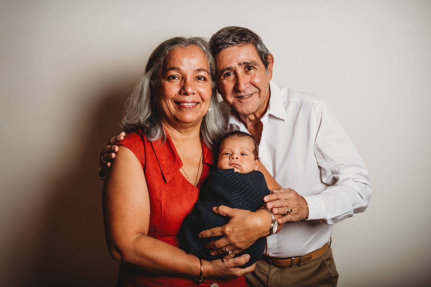Family portrait featuring three people against a light neutral background.