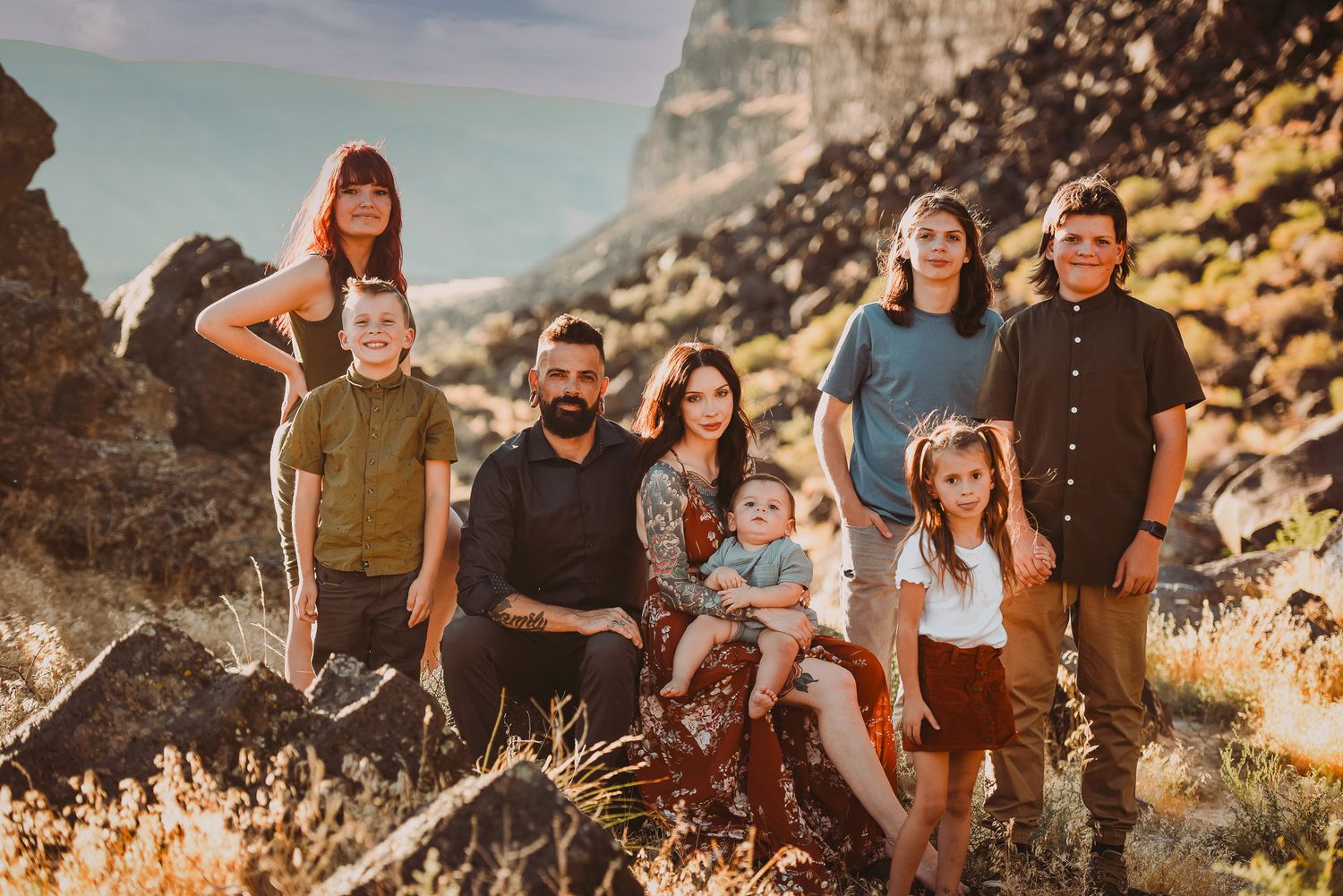 Family group poses together on mountainside during sunset photoshoot.