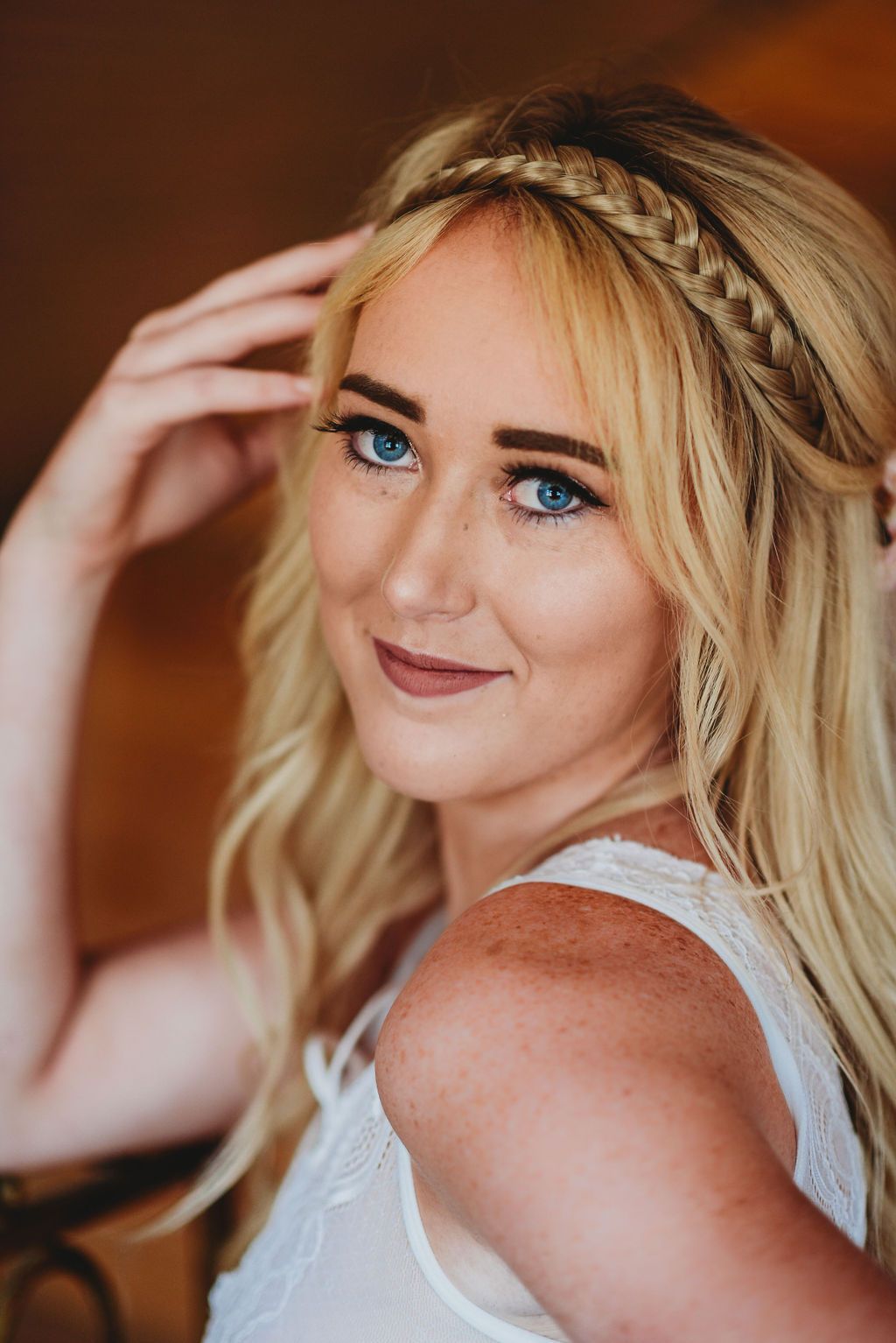 Elegant bridal portrait featuring braided hairstyle and natural makeup in warm lighting.