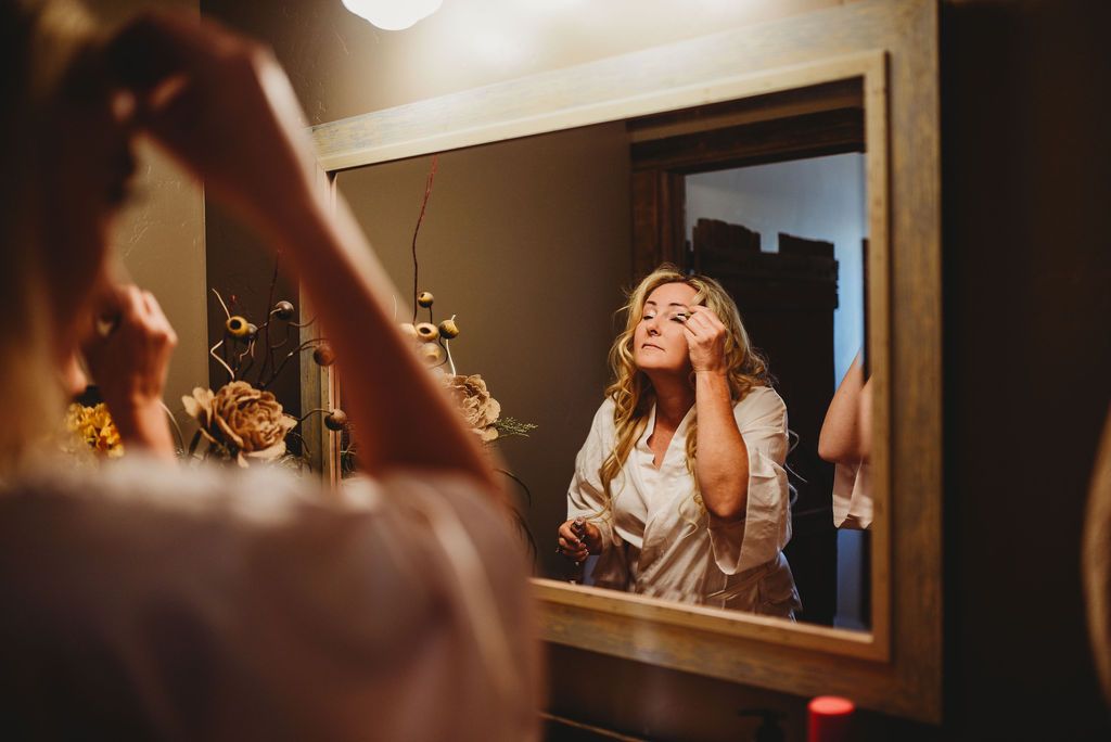 A reflection in a mirror shows preparation moments with warm lighting and floral arrangements.