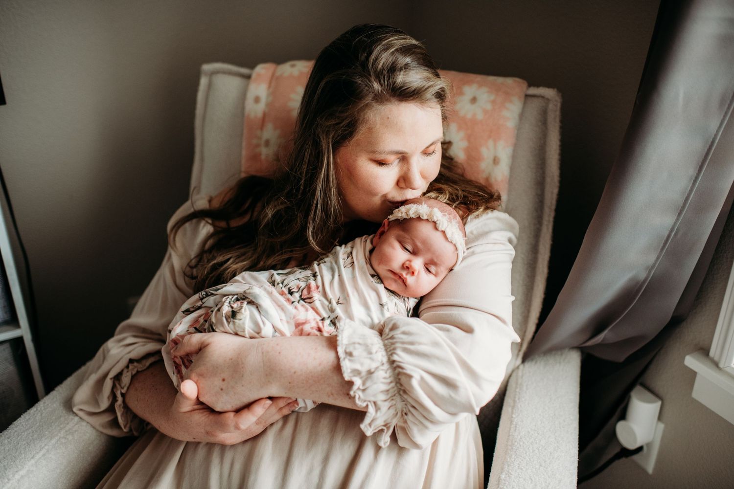 A tender moment captured between mother and newborn baby as they rest together in a cozy nursery chair.