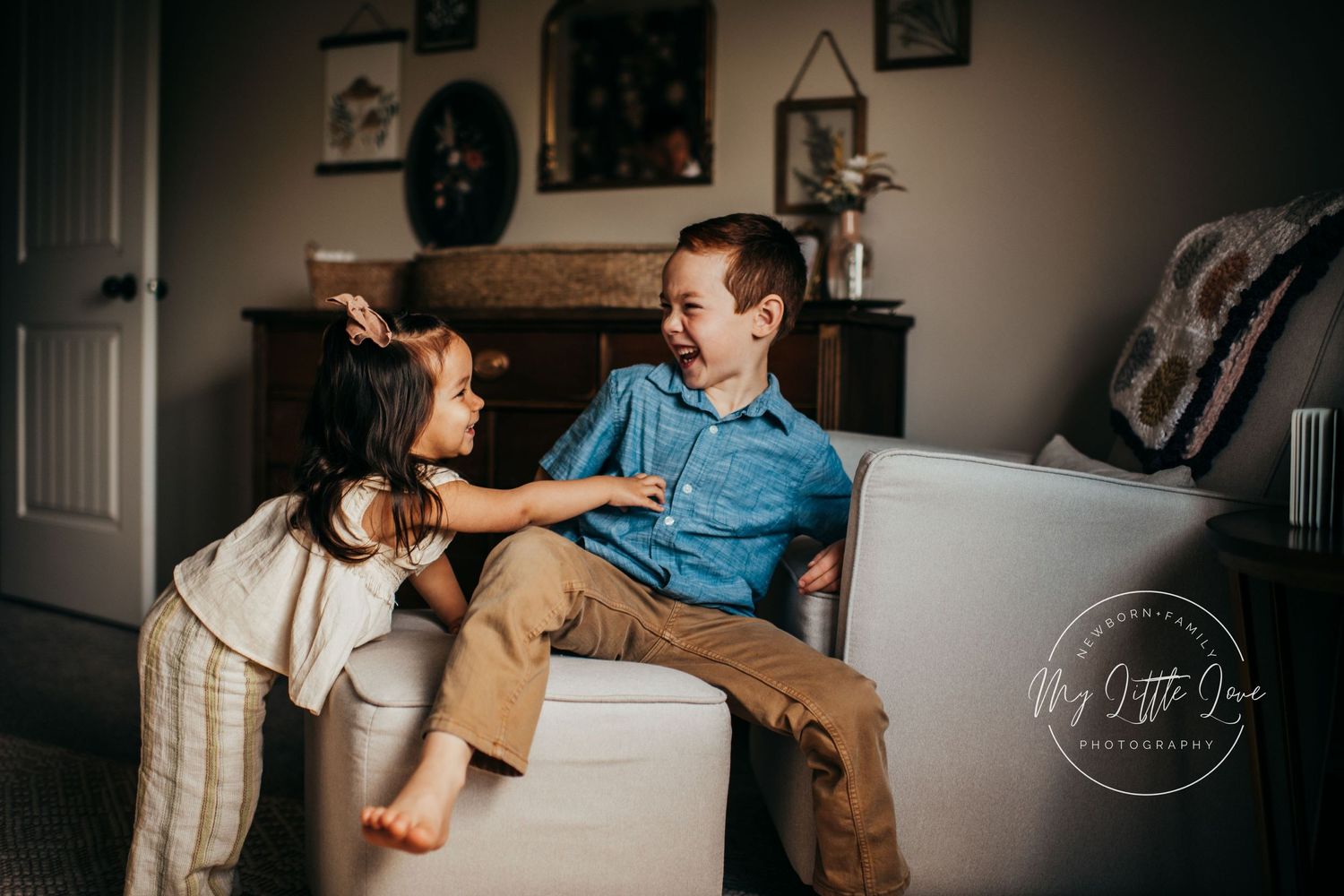 A playful candid moment between two people sitting on a cream colored couch in a cozy living room.