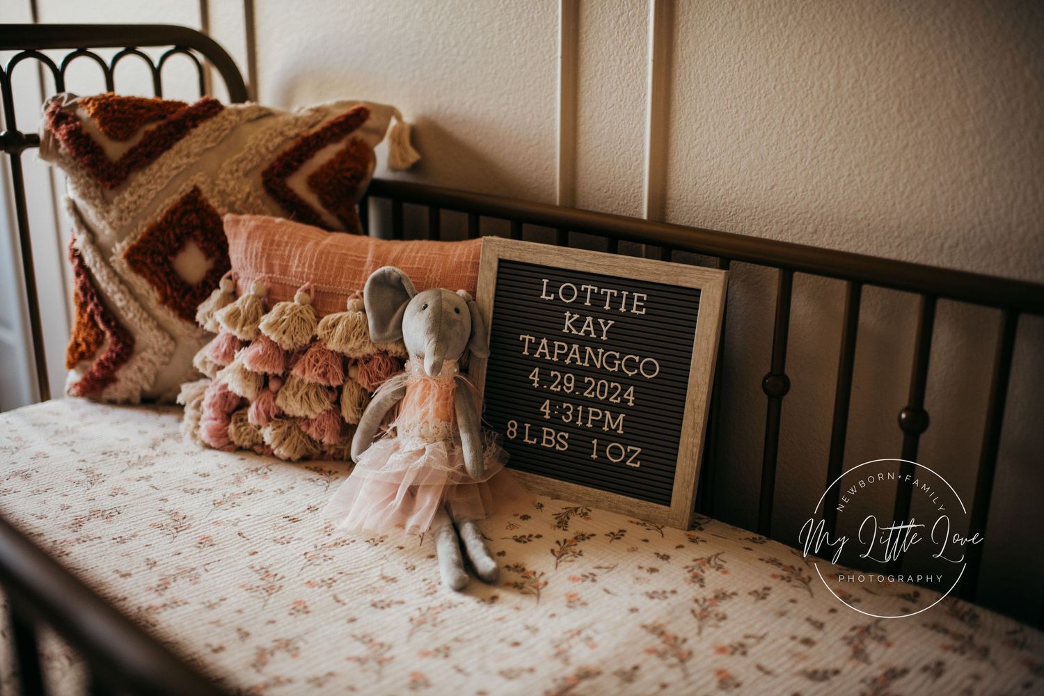 A cozy bedroom corner with a letter board sign and plush toys on floral bedding.
