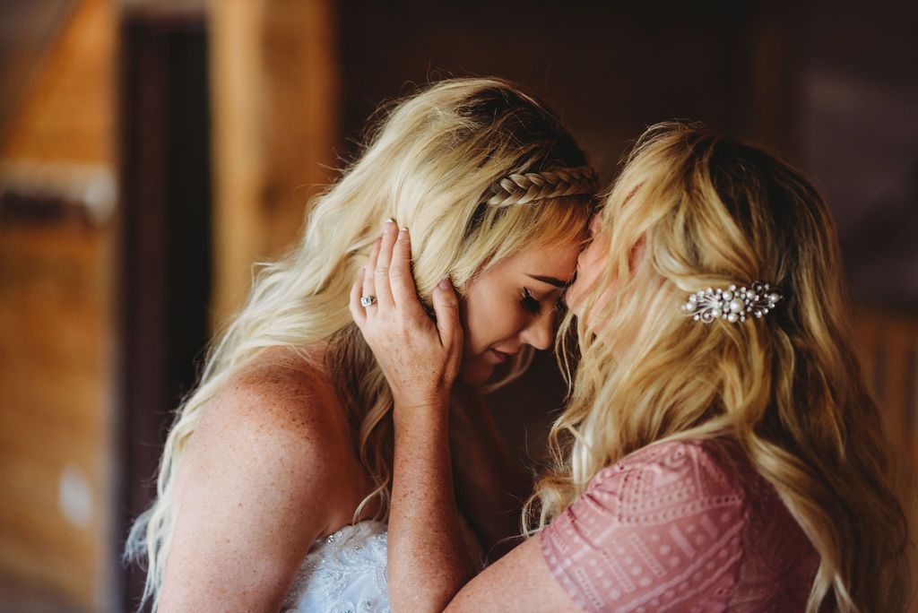 Two people share an emotional moment in pink dresses with blonde hair and decorative hair accessories.
