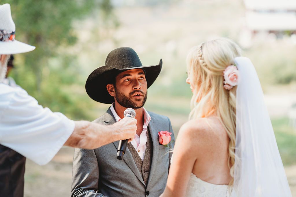 A countryside wedding ceremony with a couple exchanging vows under bright sunlight.