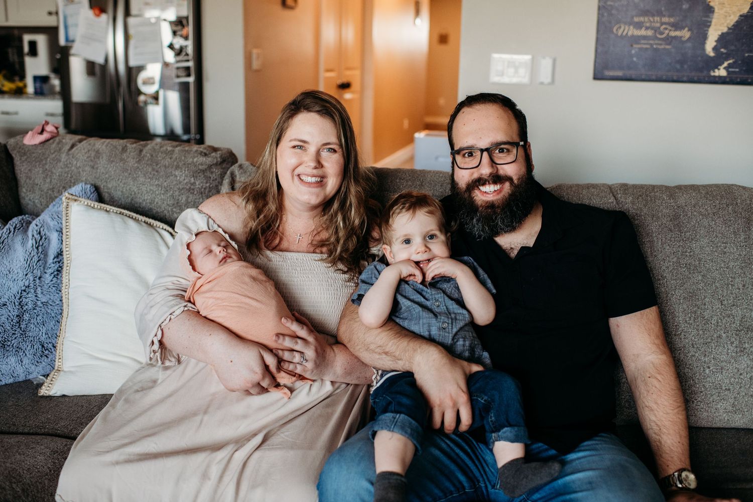 A family relaxes together on their living room couch in a candid at-home portrait.