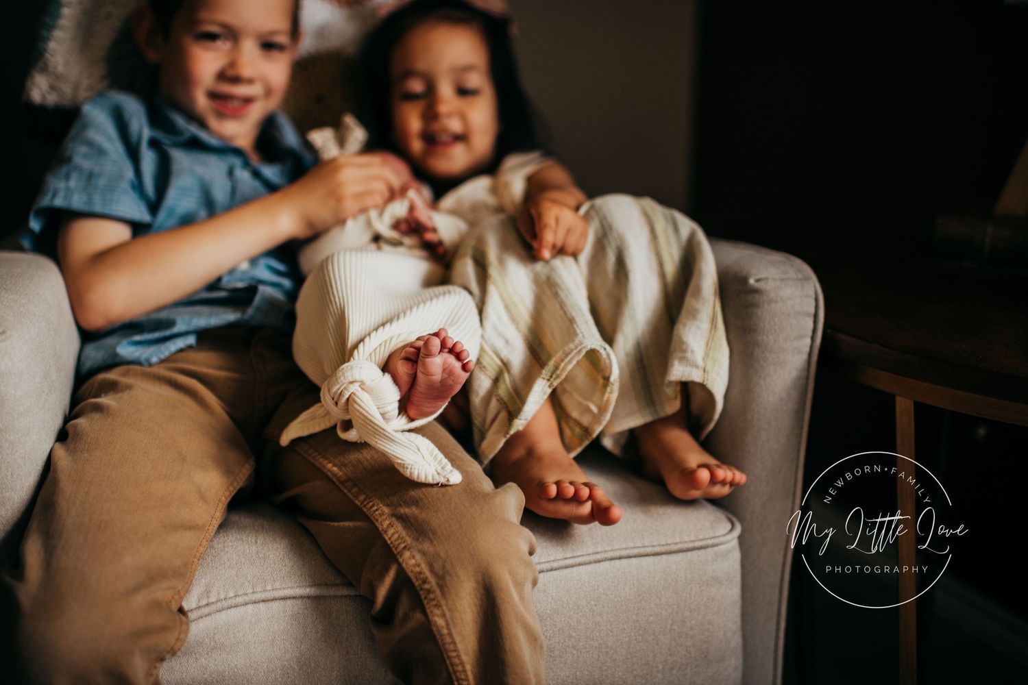 Children sitting together on light colored couch sharing joyful moment.
