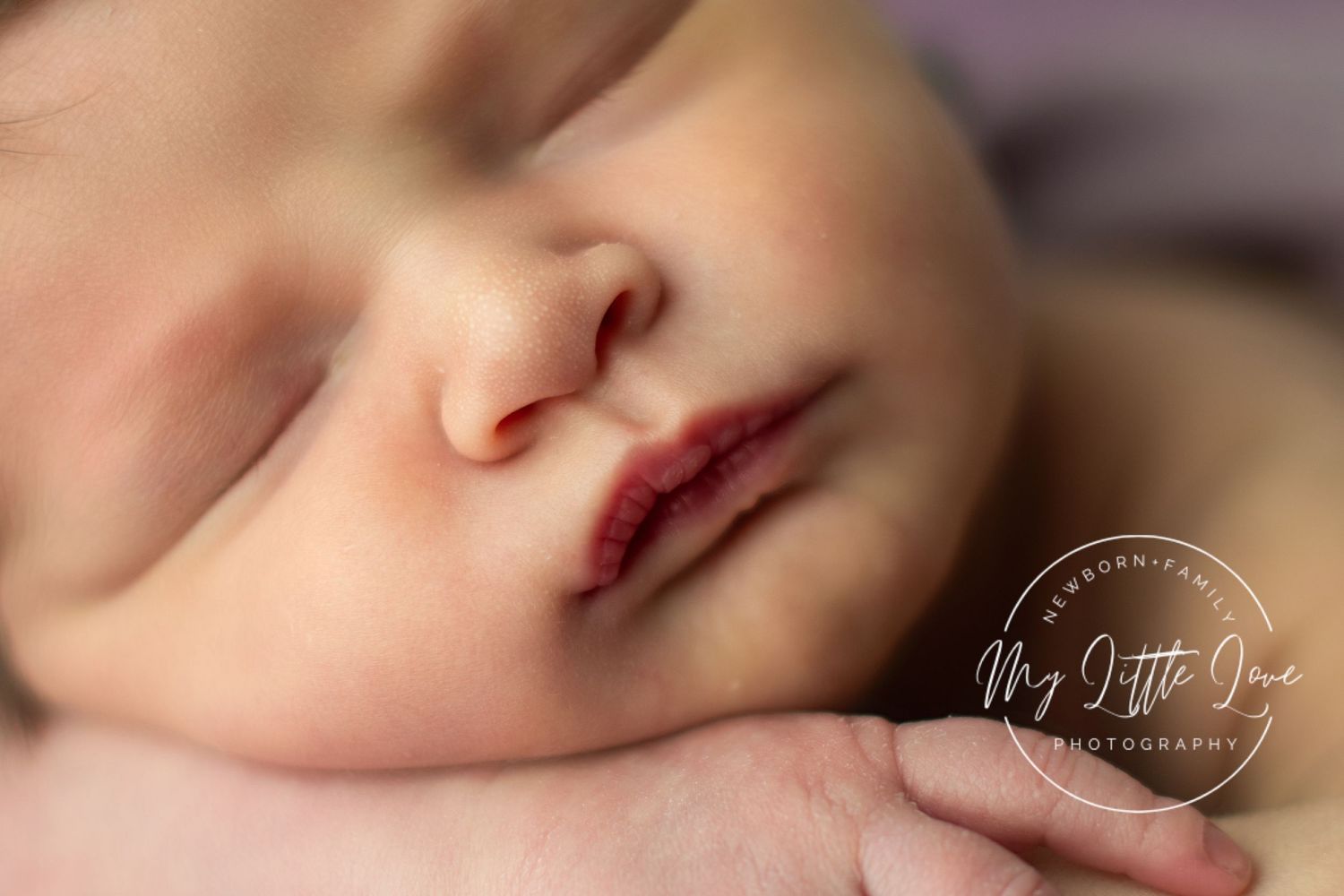 Close-up macro photograph of a sleeping baby's face with soft lighting and shallow depth of field.