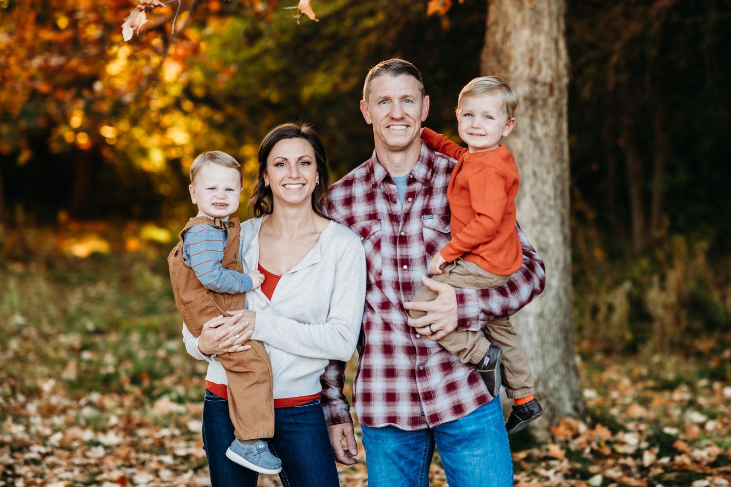 Family portrait in autumn forest with colorful fall foliage.