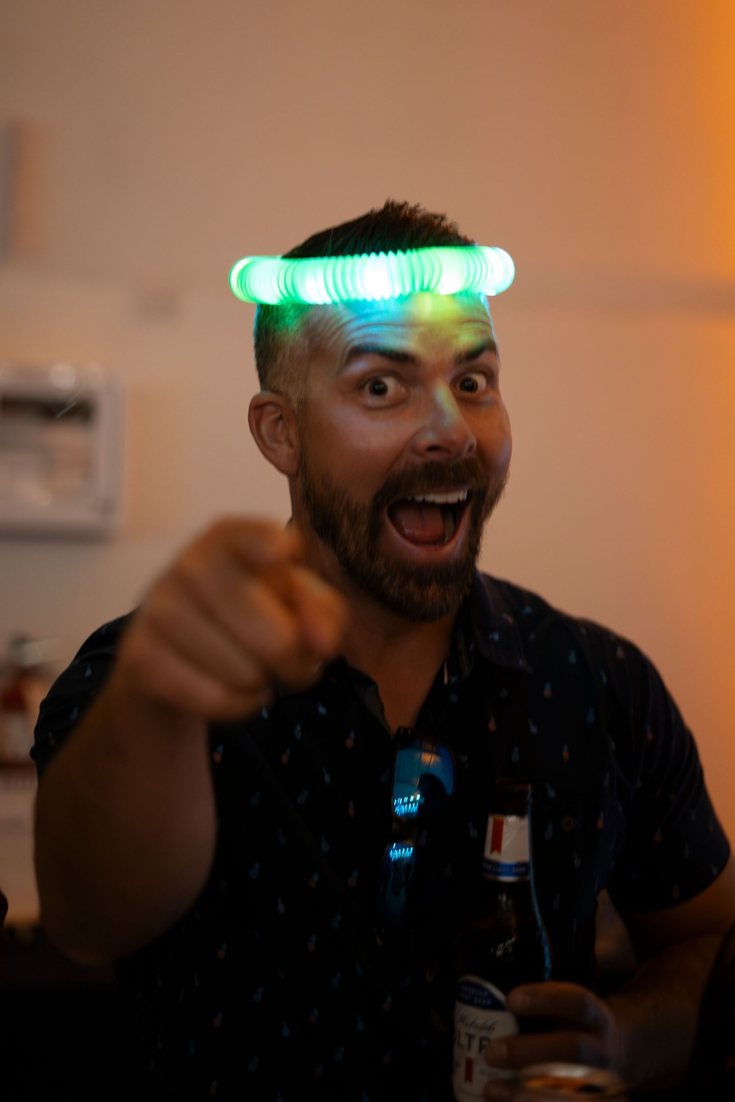 Person in black shirt making animated expressions with green lights glowing on head.