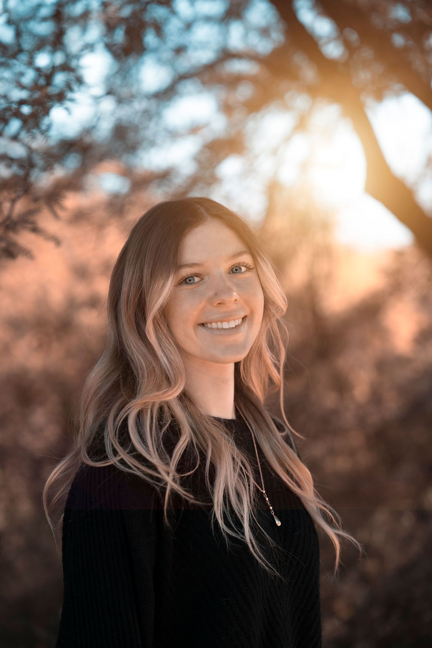 Artistic portrait with warm sunset backlighting through autumn foliage.