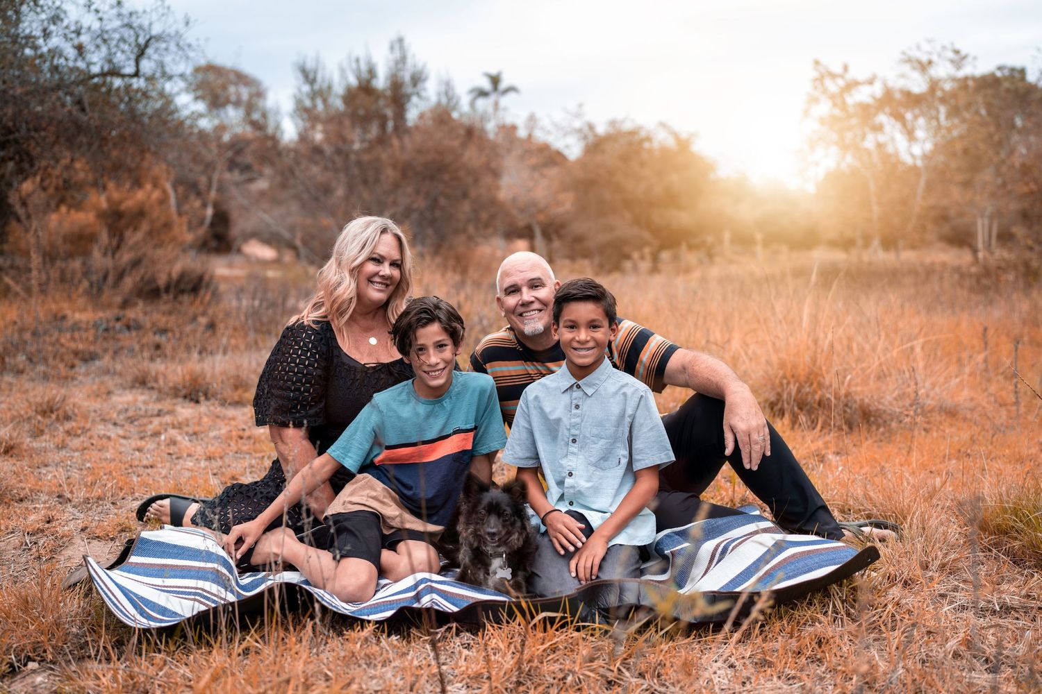 Casual outdoor family photos with relaxed poses in a golden autumn field at sunset.
