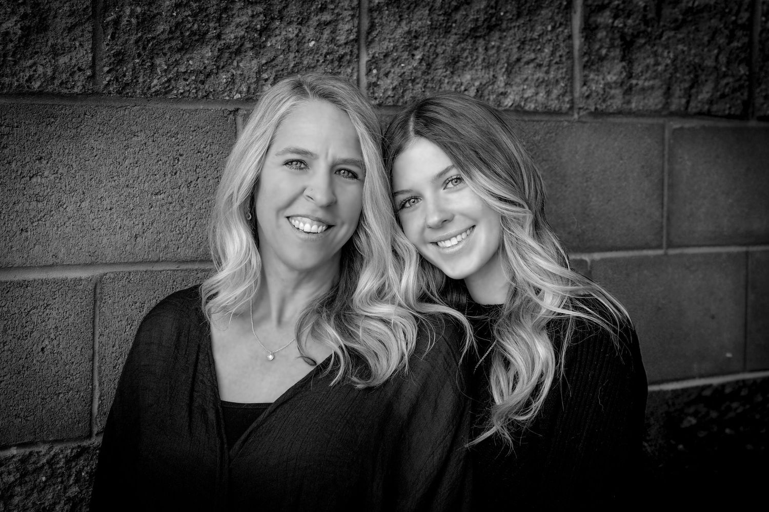 Professional black and white portrait series showing casual poses against a textured wall.