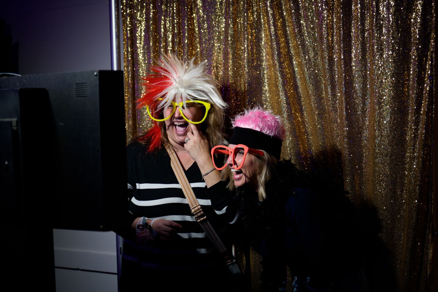 People posing against a gold sequin backdrop in dramatic lighting creating silhouettes and shadows.