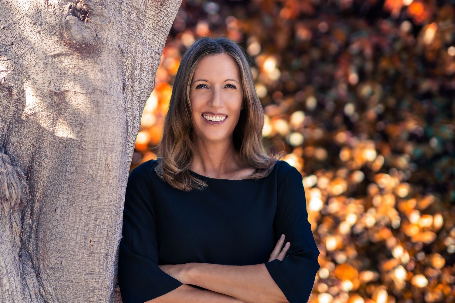 Professional headshot against blurred autumn background.