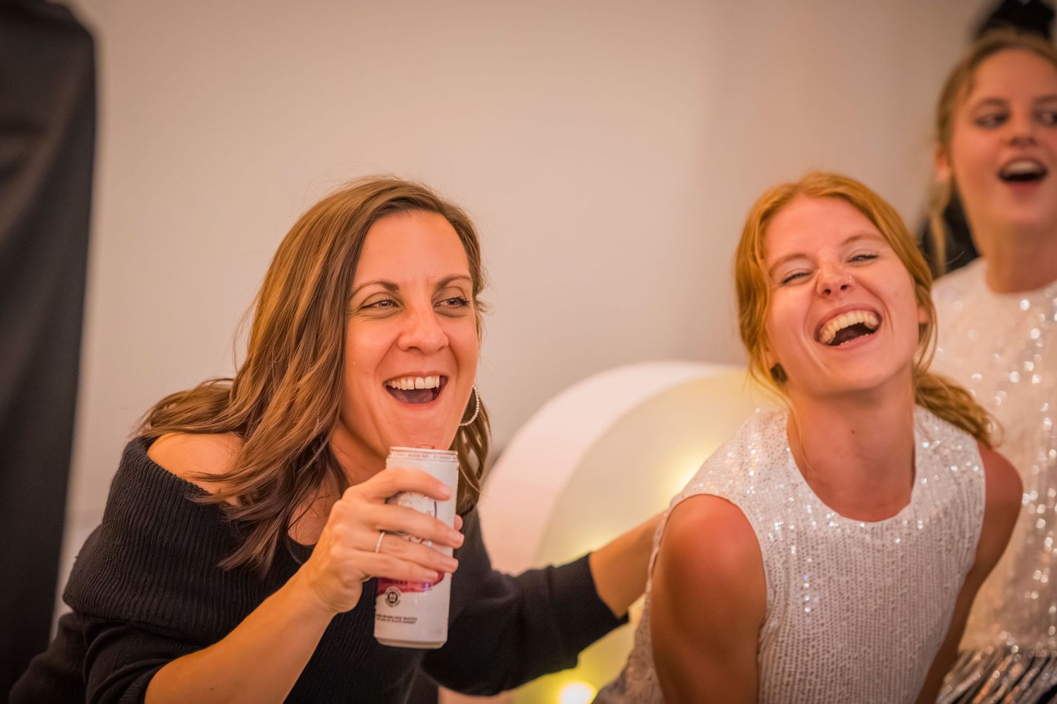 People laughing and socializing at a lively indoor gathering.