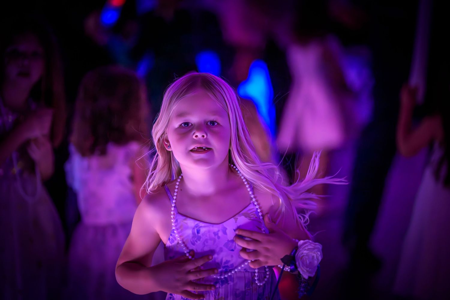 Concert crowd illuminated by vibrant purple and blue stage lighting creates an atmospheric nightclub scene.