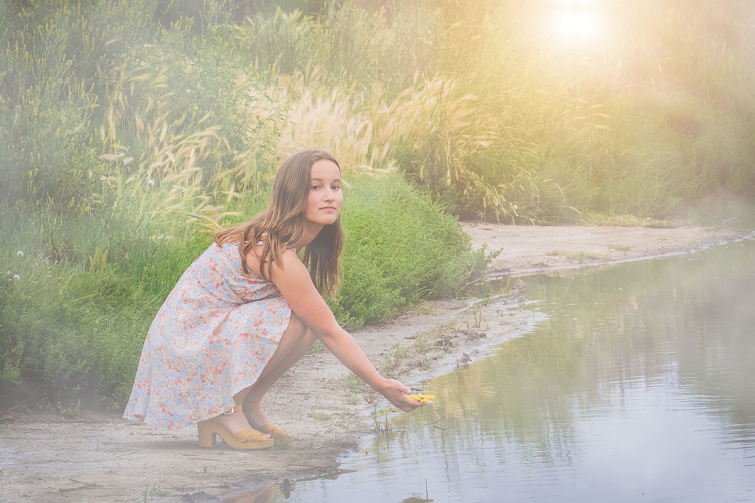 Dreamy riverside portrait with soft sunlight and natural scenery.