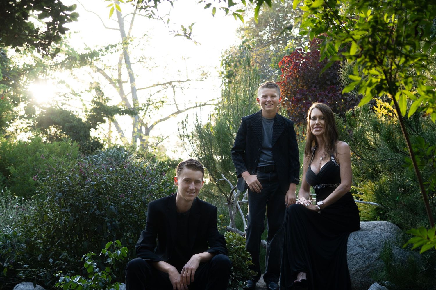 Natural family portraits in a lush green garden setting with soft lighting.