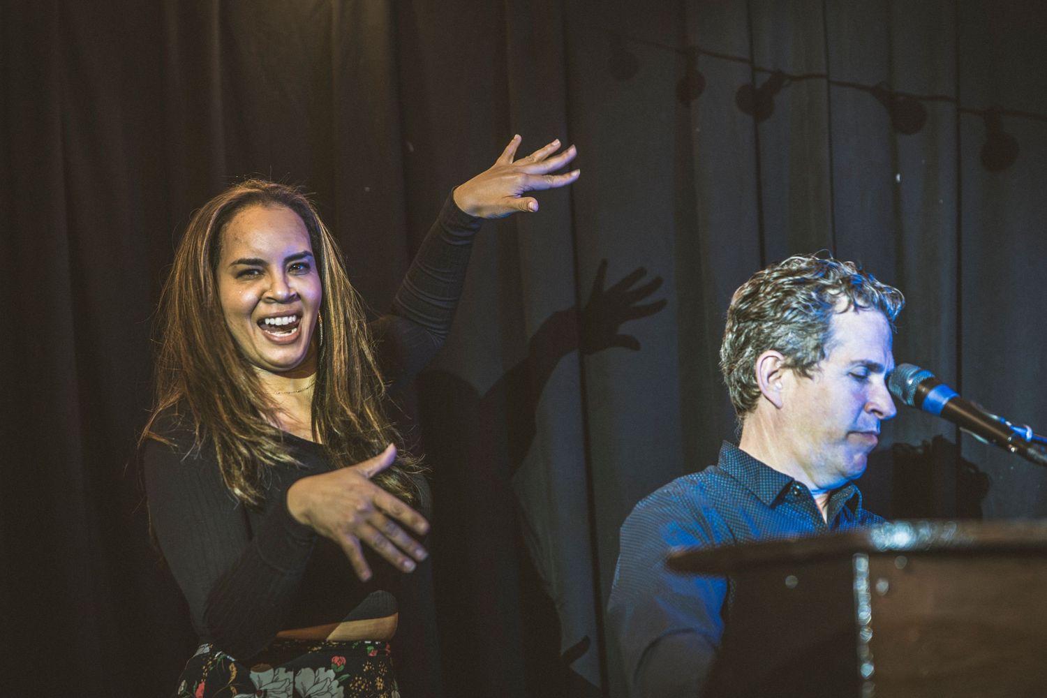 Musicians performing on stage with dramatic lighting and expressive gestures during a live show.