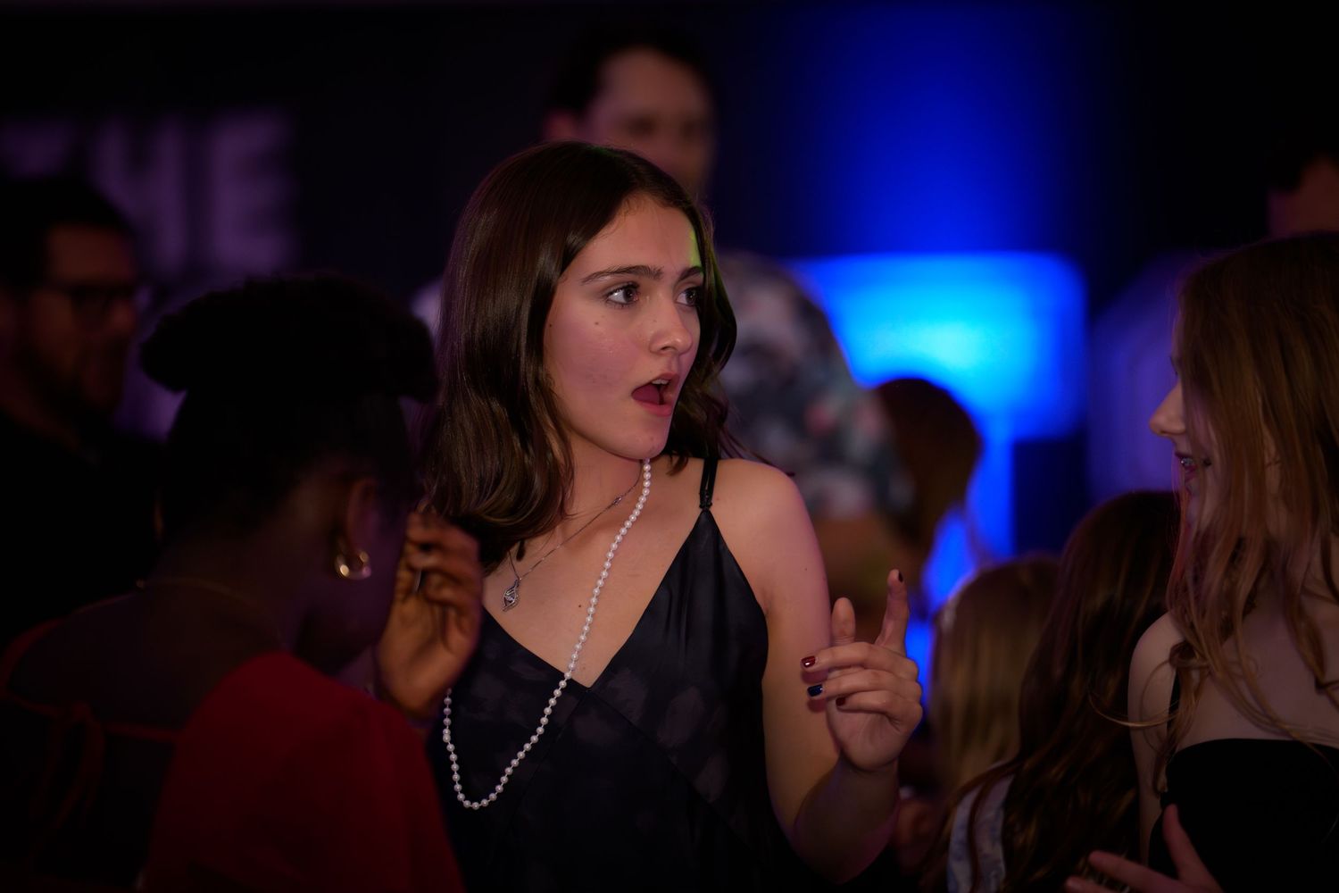 People dancing and socializing at a nightclub with blue lighting and dark atmosphere.