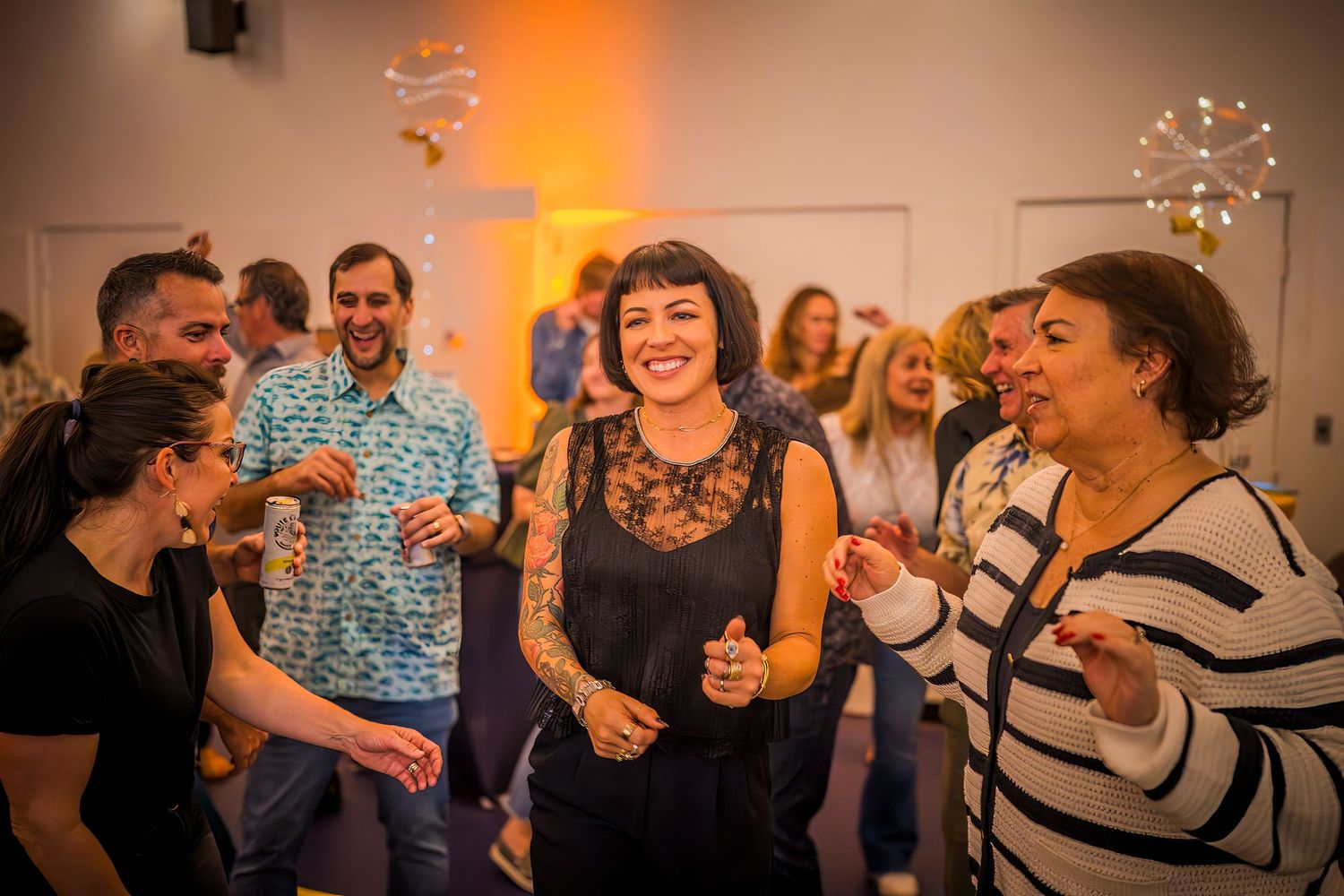 Group of attendees sharing laughs and enjoying themselves at an indoor social event.