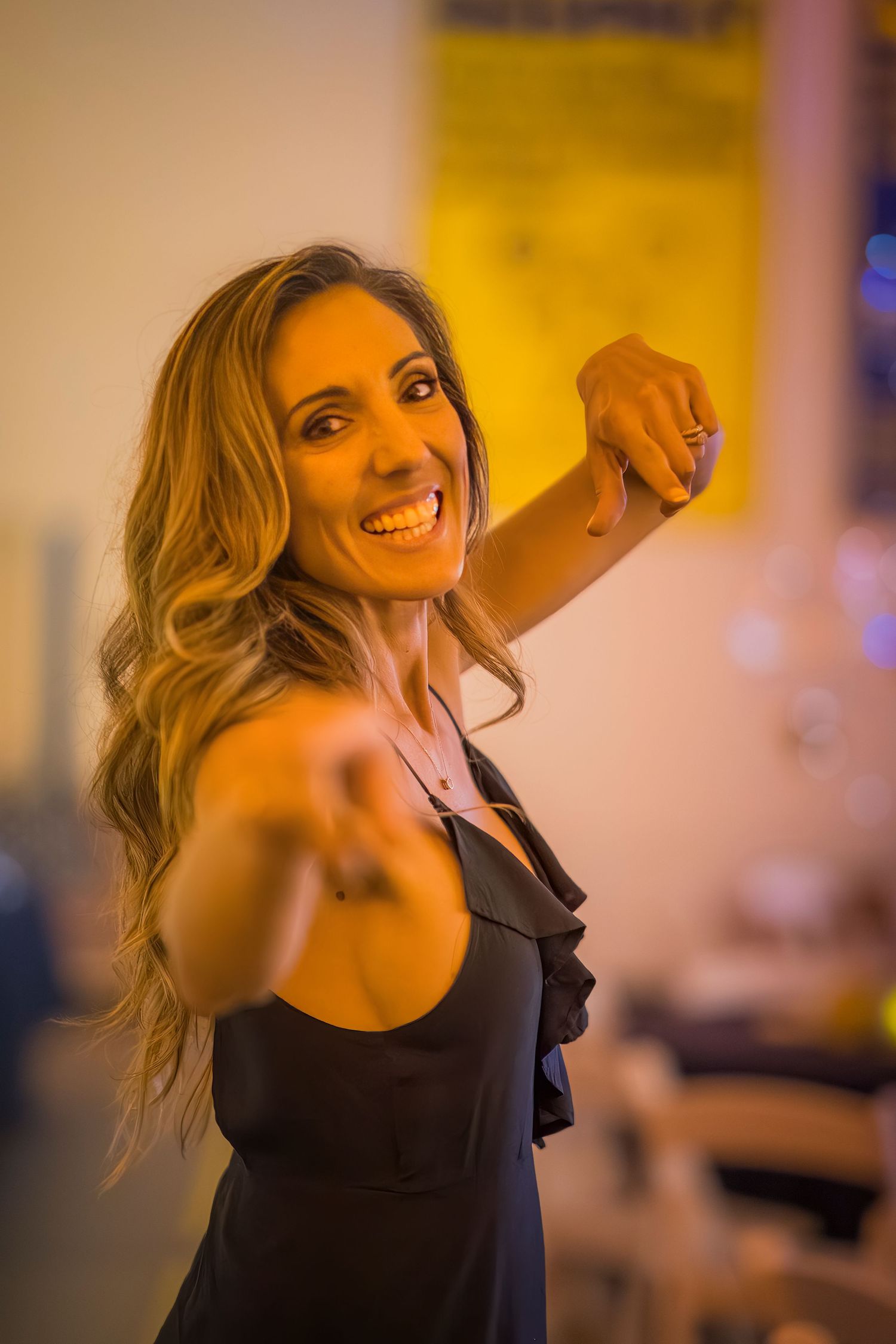 Woman in black dress having the time of her life at an indoor venue.
