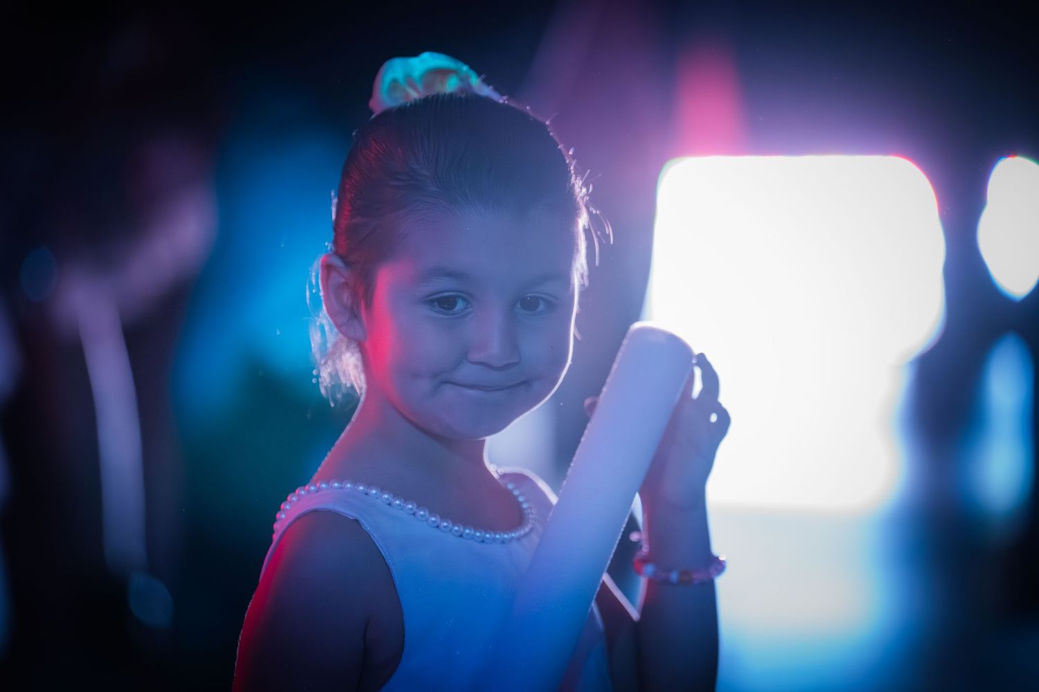Dramatic portrait in blue and pink lighting against dark background with moody atmospheric effects.