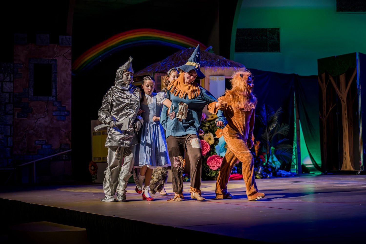 Theater performers in dark costumes on stage with dramatic lighting effects.