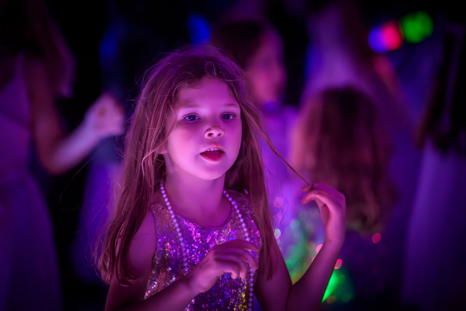 People dancing and enjoying themselves under dramatic purple lighting at a nightclub or party event.