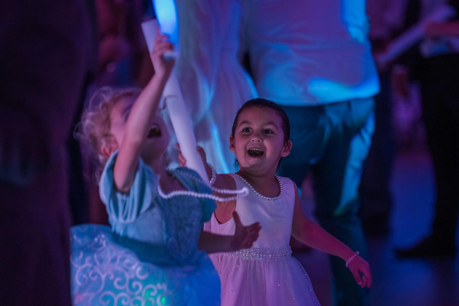 Children dance and celebrate at a party illuminated by vibrant blue lighting.