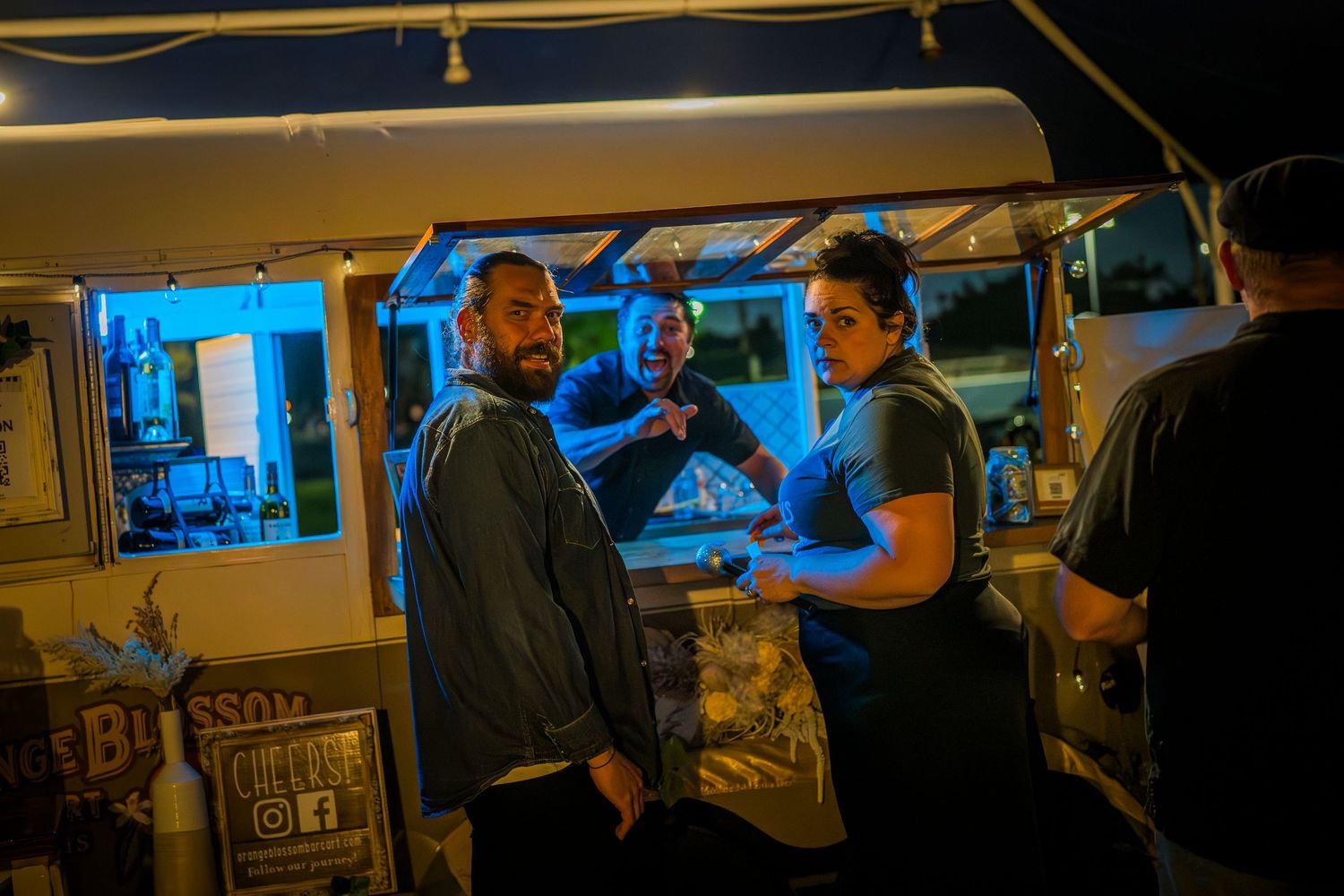 Dark venue interior with silhouettes of people getting drinks from the mobile bar.