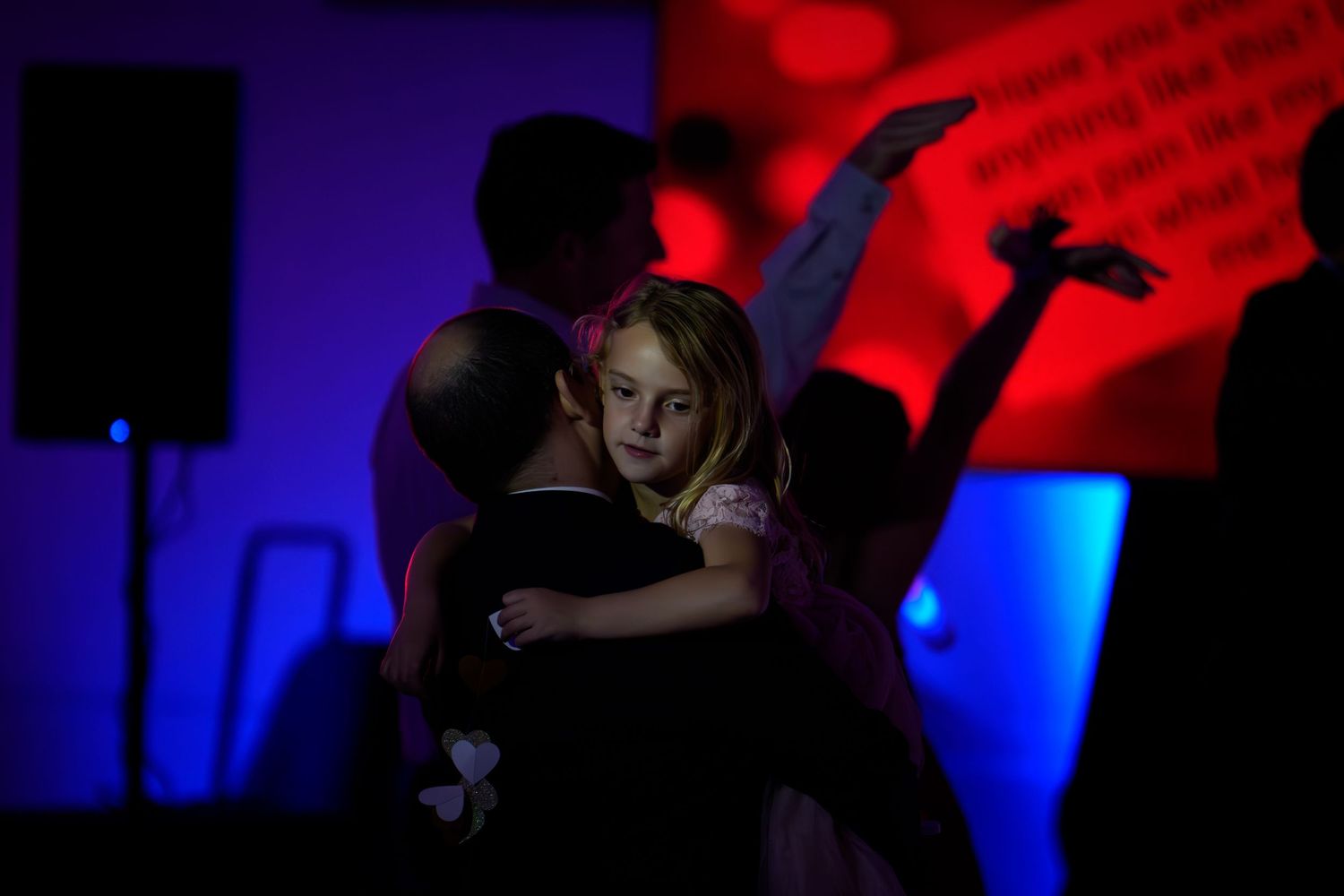 Silhouettes of people dancing in a nightclub with red and blue lighting effects creating a dramatic atmosphere.