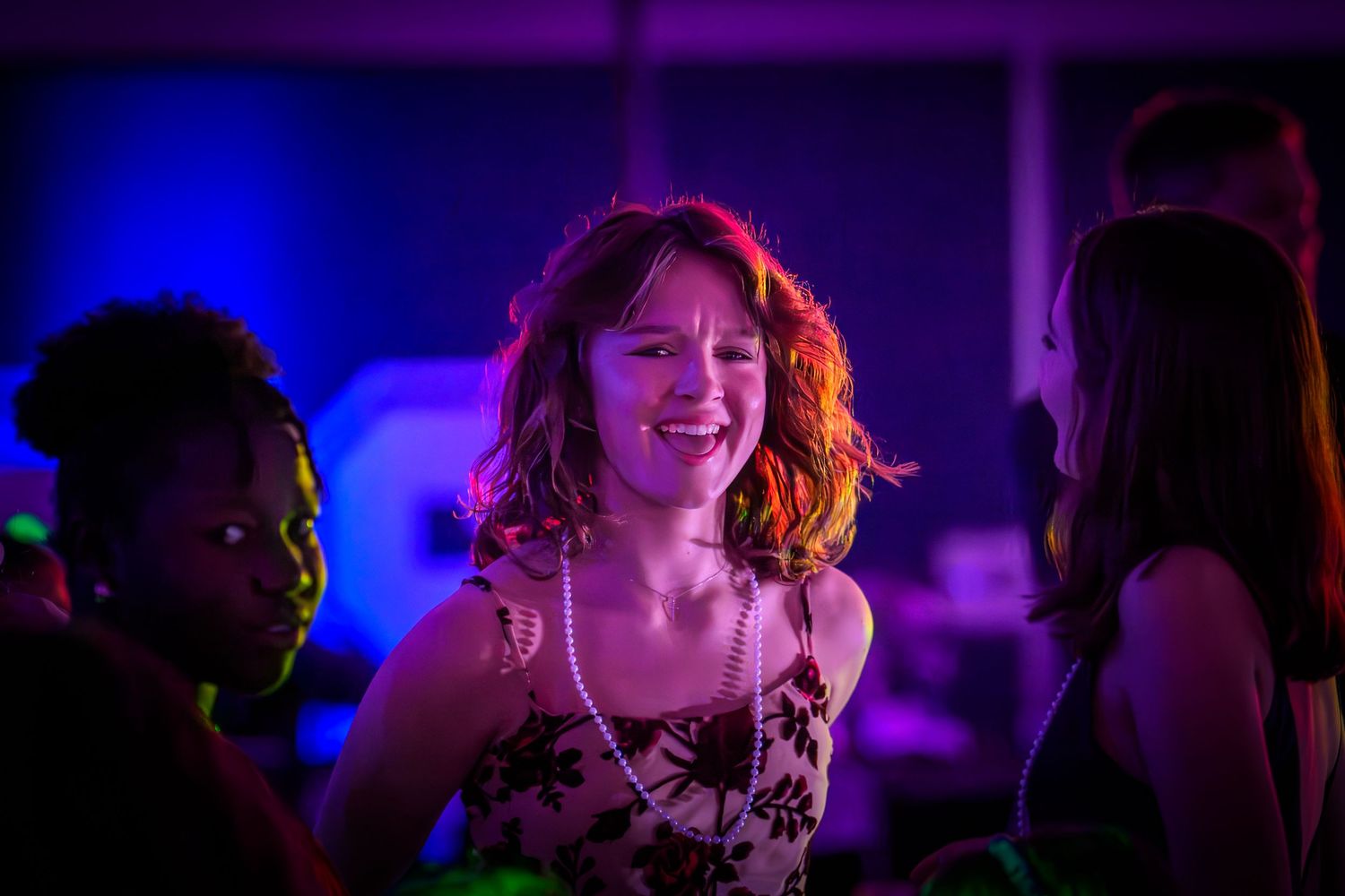 People dancing and enjoying themselves in a dark nightclub with blue and purple lighting effects.