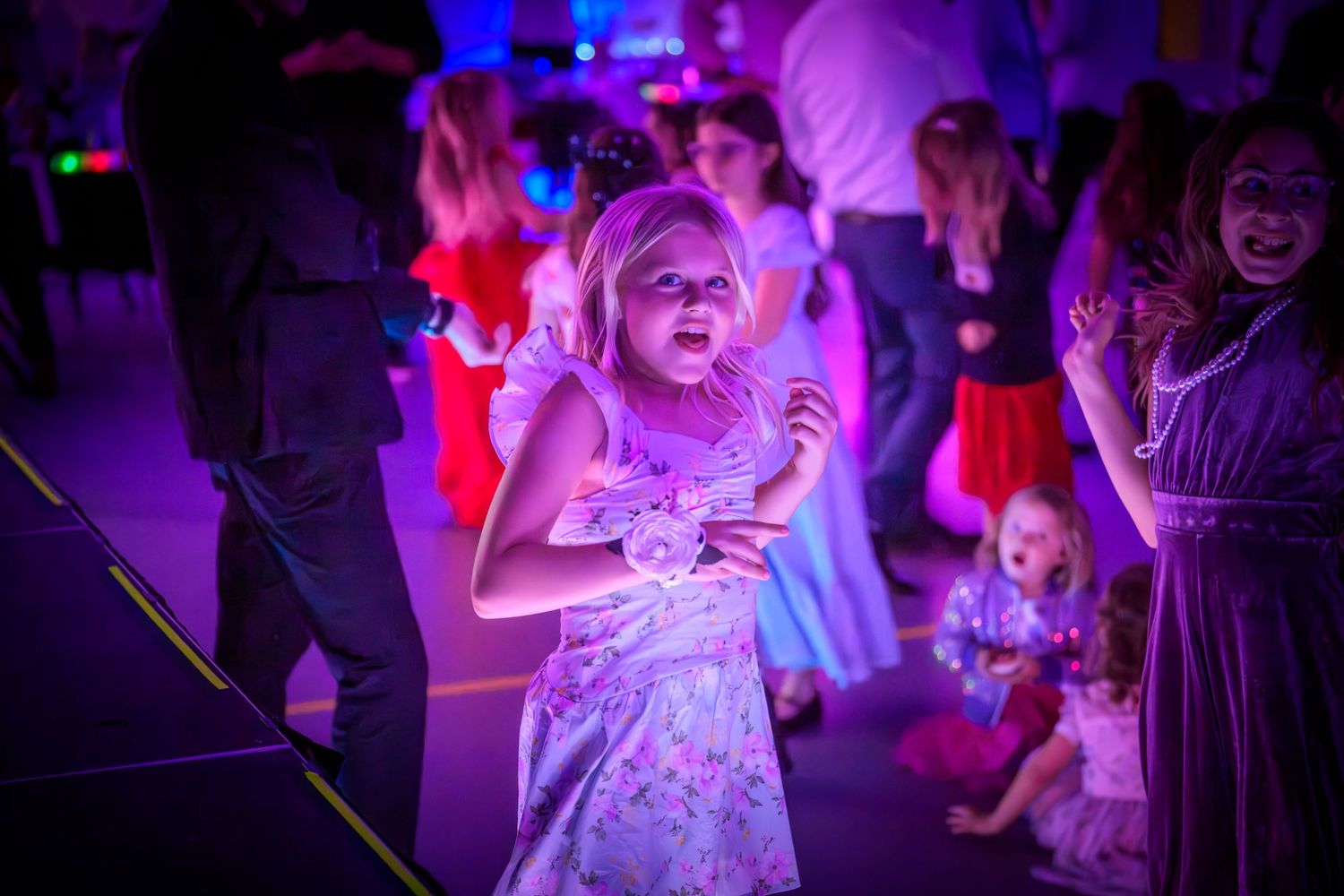 Energetic dance party scene with people moving under blue and purple lighting effects.