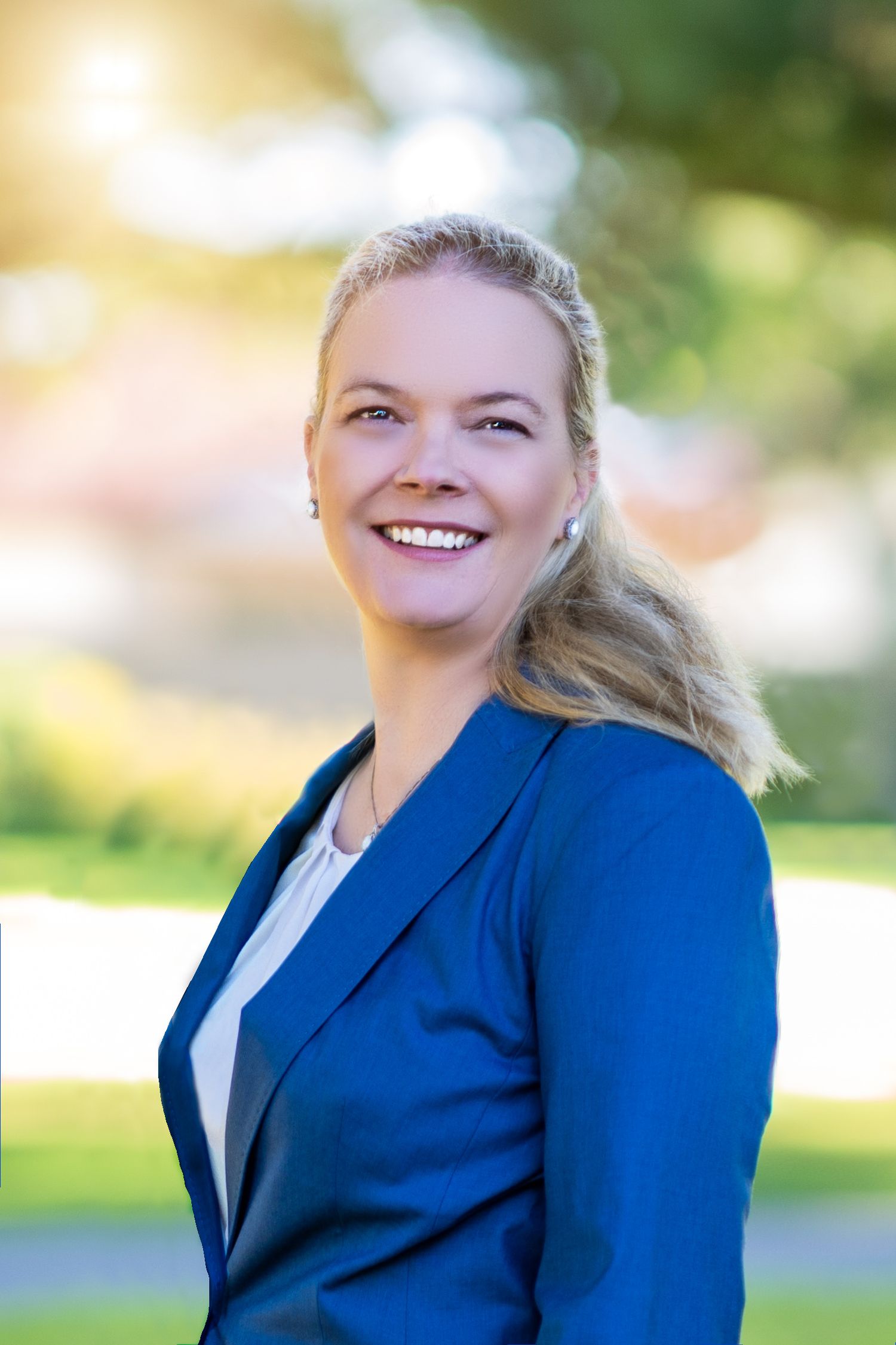 Professional portrait in a royal blue blazer taken outdoors with natural lighting.