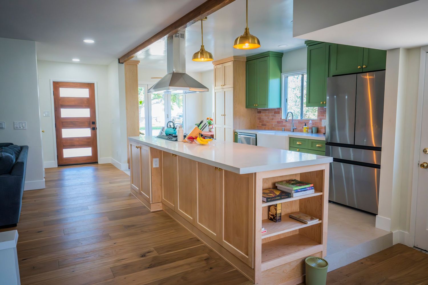 Contemporary kitchen and dining area featuring wood floors, pendant lights, and green accent walls.