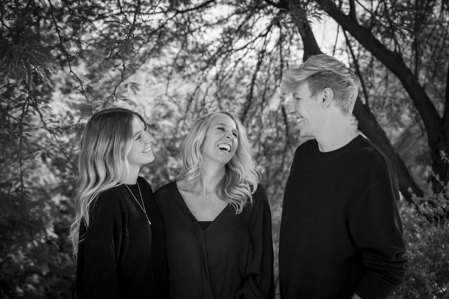 Black and white candid portraits under trees showing natural expressions and laughter.