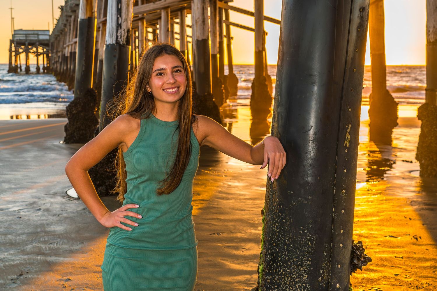 Sunset photoshoot under pier with golden light reflecting off water.