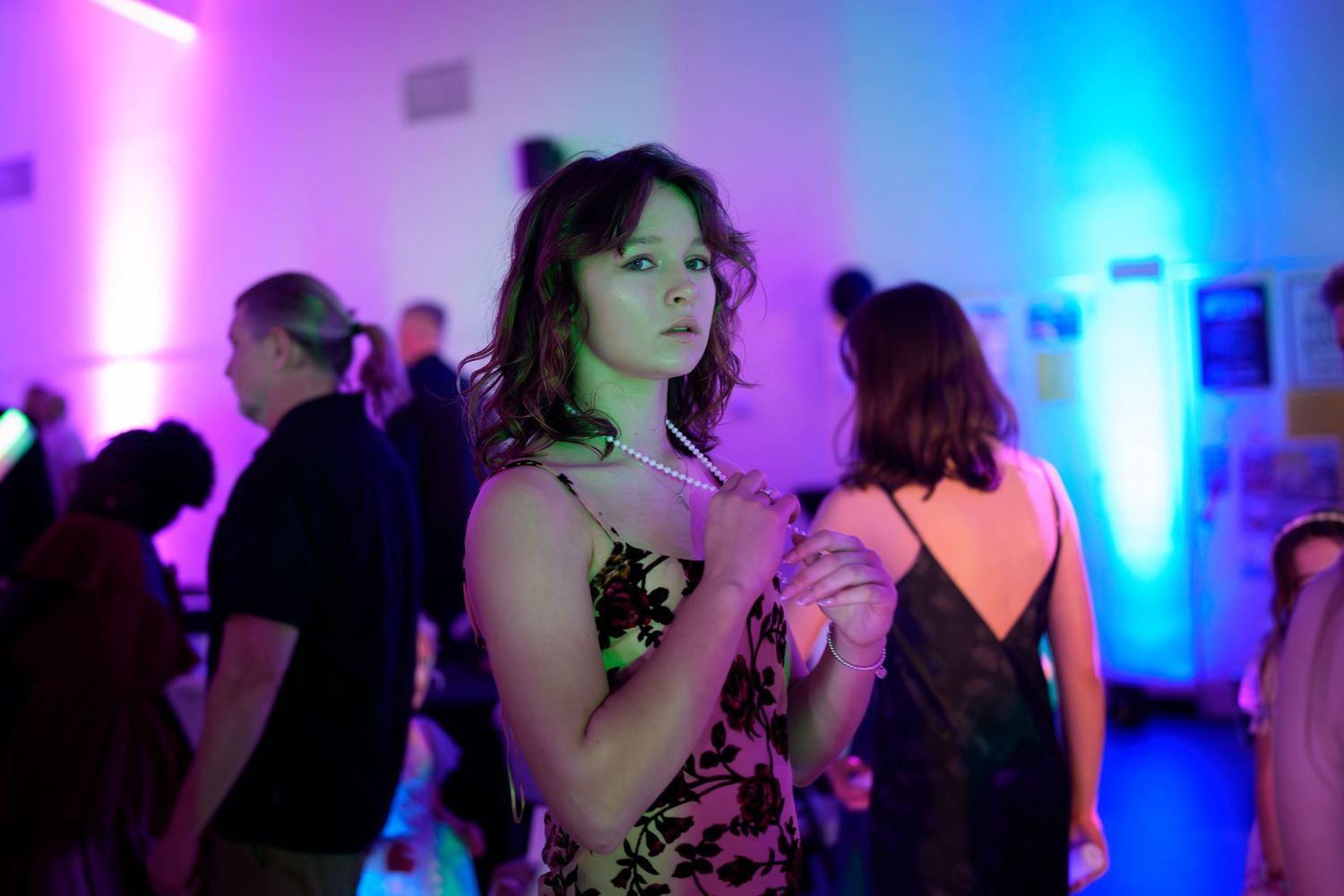 Silhouettes of people dancing at a nightclub with vibrant pink and blue lighting creating an energetic atmosphere.