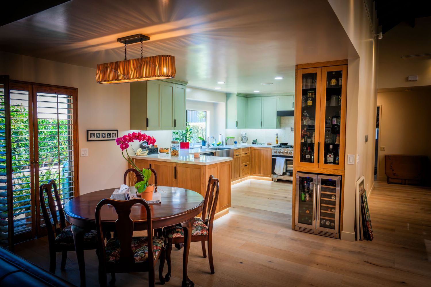 Modern interior panorama showing open concept living space with hardwood floors and natural lighting.