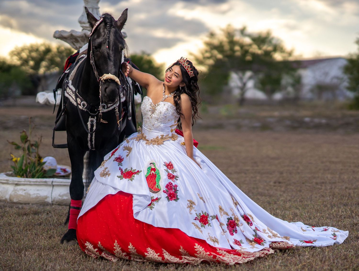 A bride in a white and red dress poses dramatically on the ground during an outdoor photo shoot.