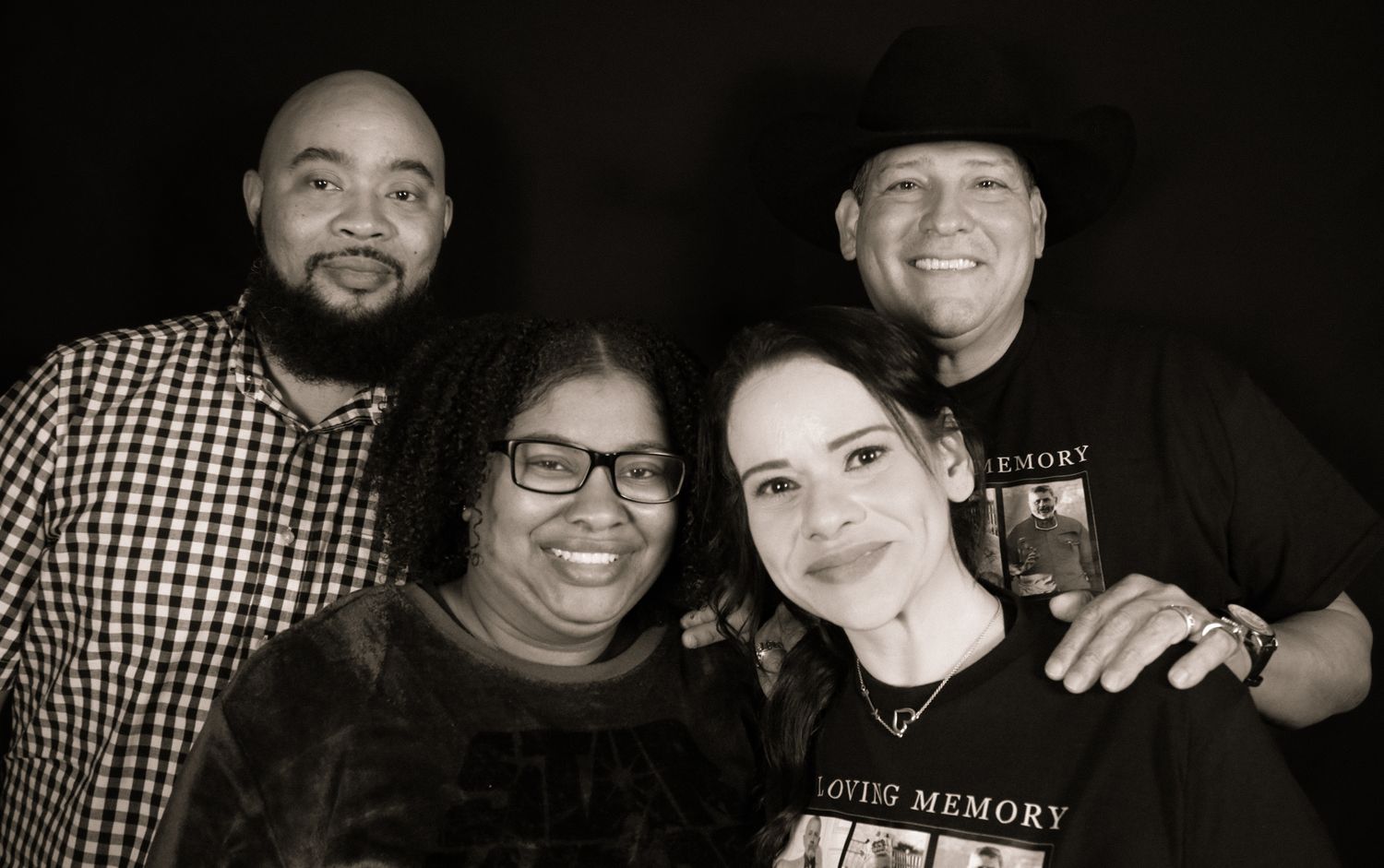 A black and white portrait style photograph of four people posing together in a casual, friendly group shot.