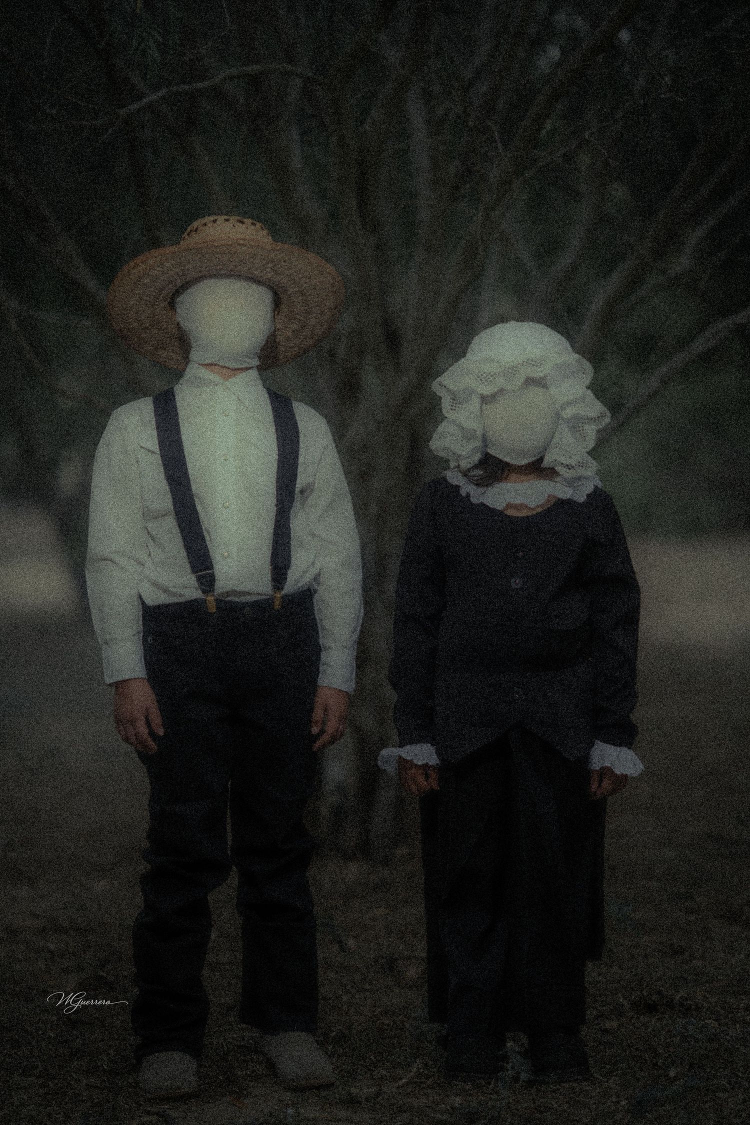 Two faceless figures in vintage clothing stand in a dark, foggy forest setting.
